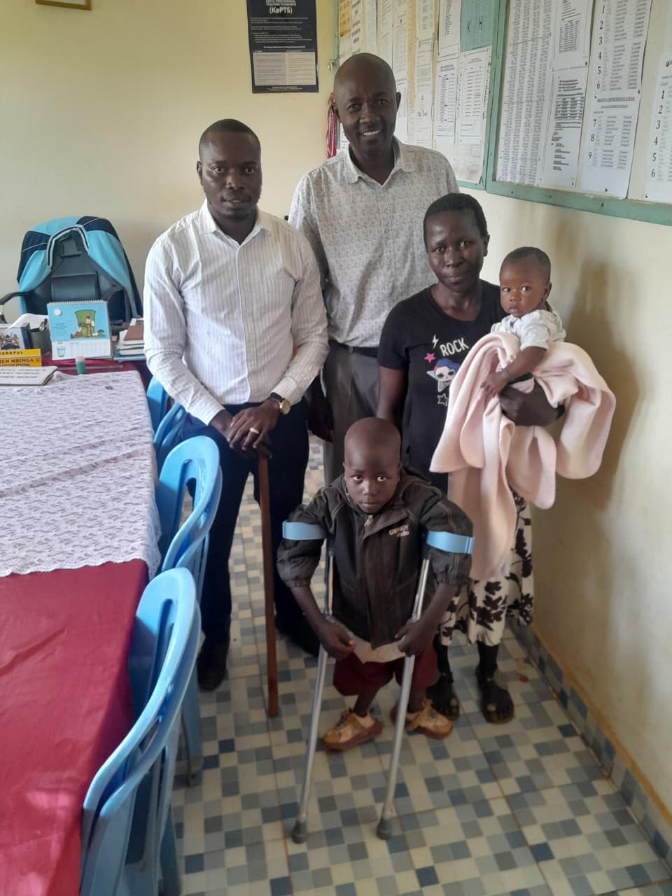 A 6-year-old boy at Karapul ECD receives a walking aid from NALFA C.B.O. volunteers during a community support initiative.