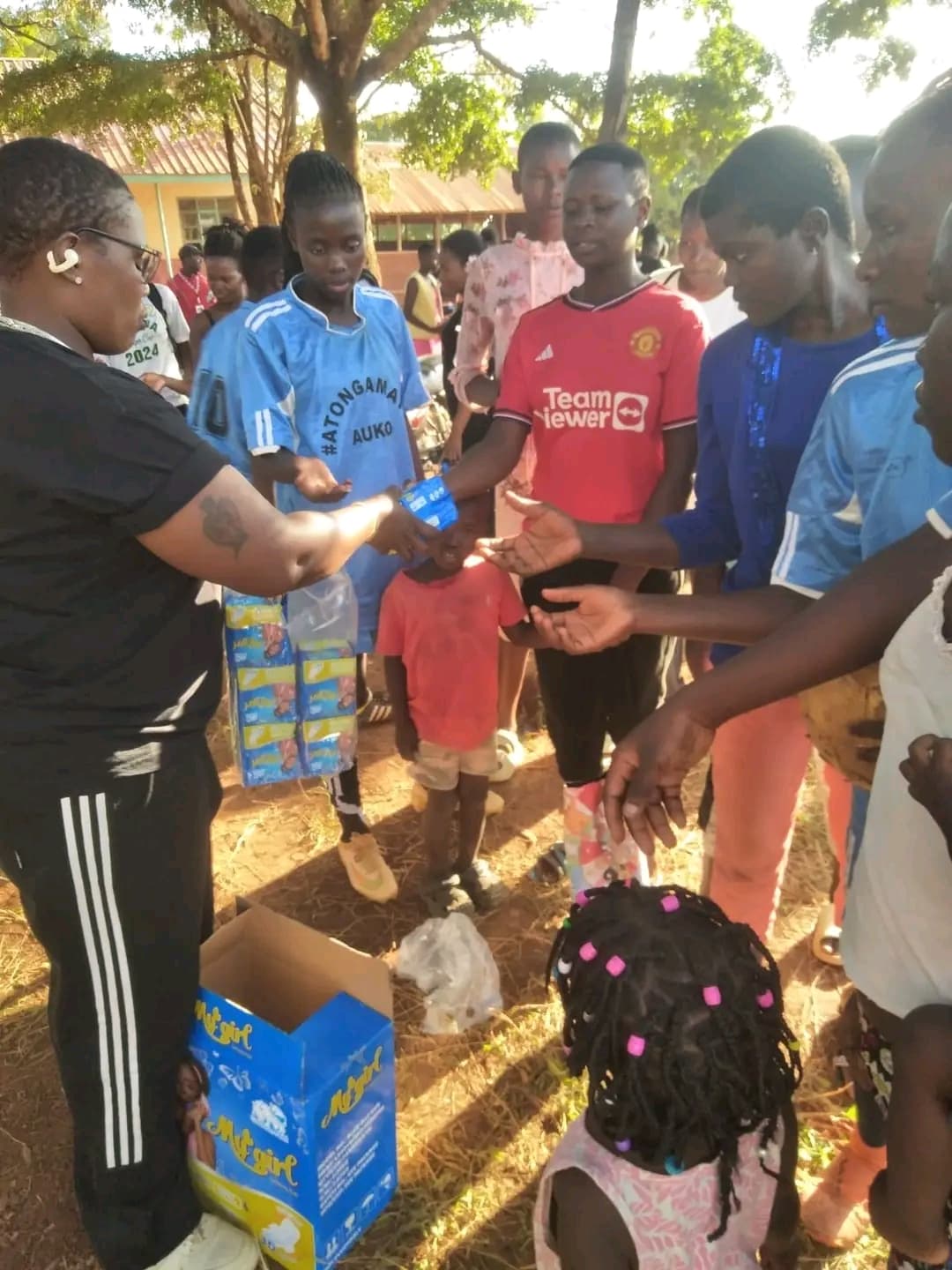 volunteer distributing free sanitary pads to girls and women during the Ndege Siaya Super Cup tournament in Siaya County, Kenya.