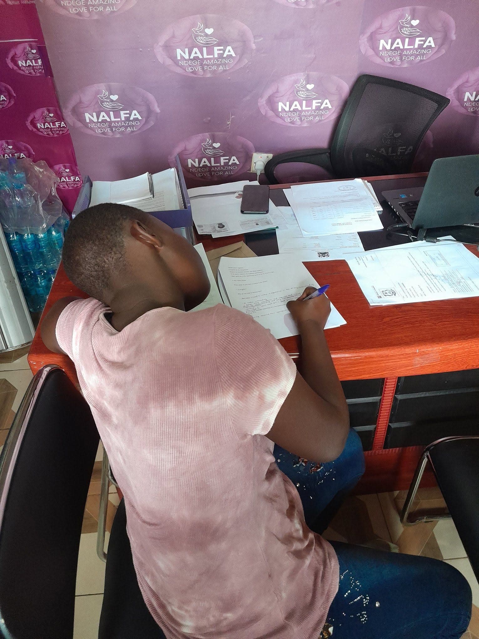 school fees beneficiary signing education support forms at the organization’s office.